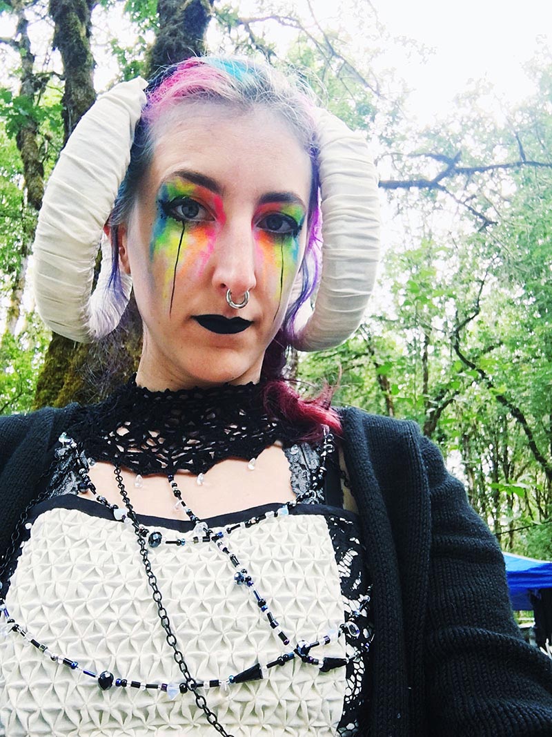 stephanie wearing horns, a lace costume, and neon rainbow dripping makeup