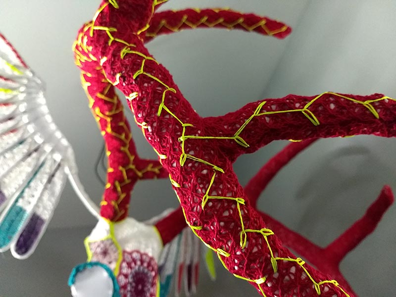 detail shot of furfur's antler, with neon yellow branches embroidered over knitted red ribbing