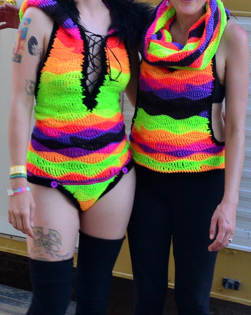 body shot of stephanie and her sister wearing a crocheted rainbow onesie and vest