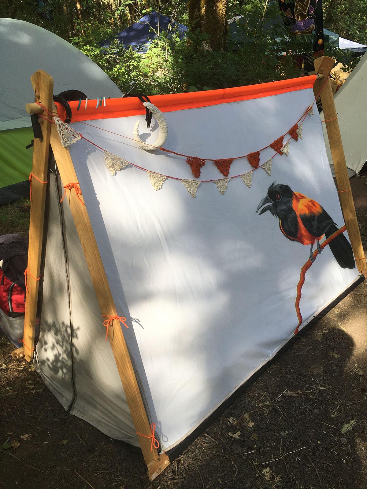 an aframe tent with the bird painting, with crocheted buntings hanging across