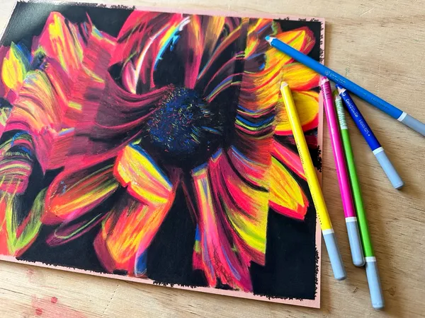 full sunflower painting next to pastel pencils