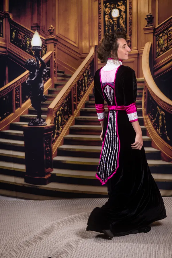 Stephanie in a black velvet 1910s gown with magenta trim. Down the back is a beaded panel that lights up.