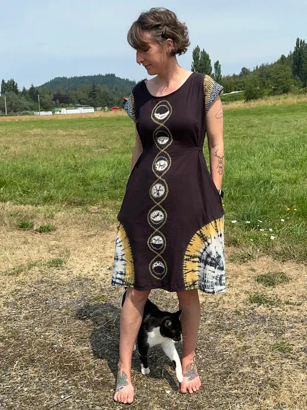 Black dress with white and yellow tie dye sections. Running vertically down the center front is the lunar chcle, the sleeves and bottom corners of the dress are concentric yellow and white rings.