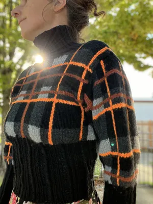 Front view of black, gray, and orange plaid sweater