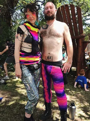 Stephanie wearing a neon rainbow, crocheted, collared, open side vest with Jason in pink and purple crochet pants.