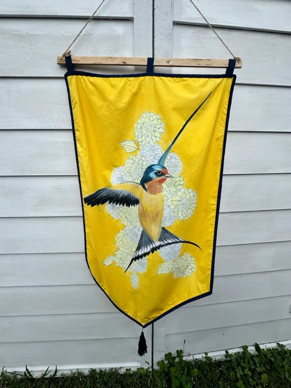 flying barn swallow over a field of white and yellow flowers on a yellow banner